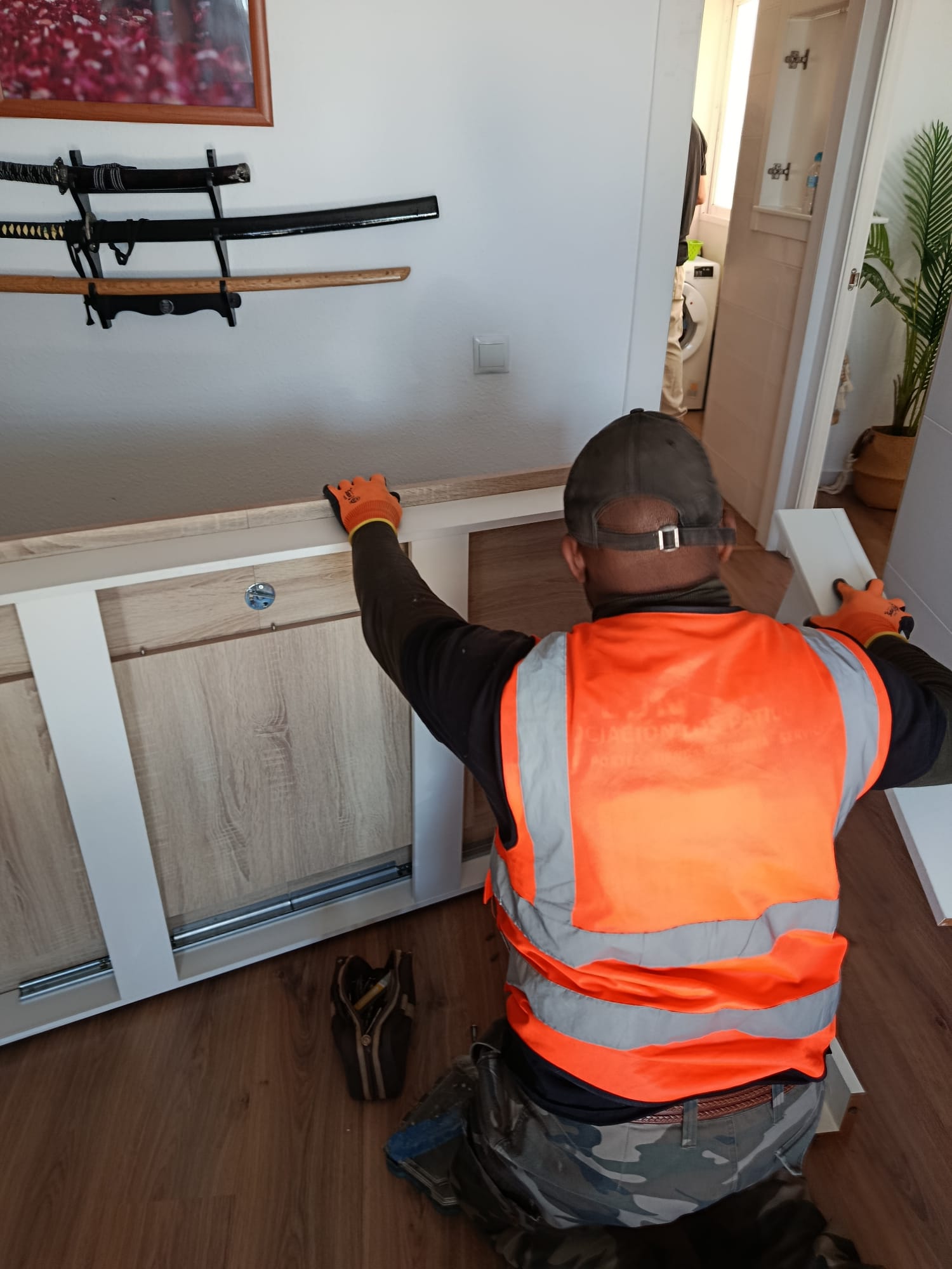 Operario con guantes naranjas montando un mueble bajo de salón